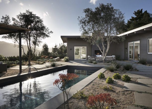 Backyard and outdoor living spaces looking over the pool to the home and mountain views